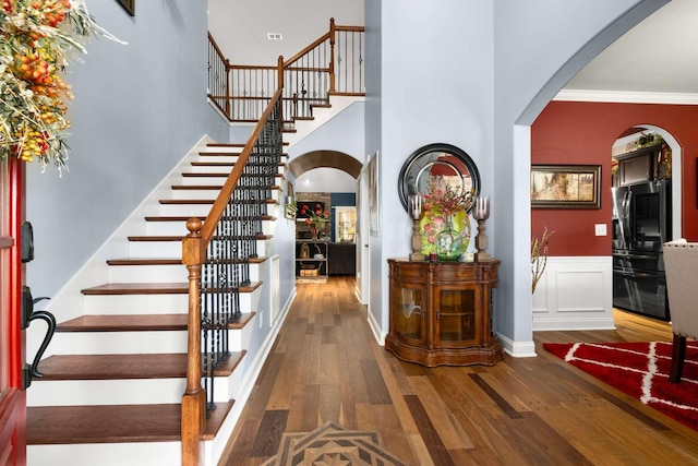 5000 Moretto Ct, Spring Hill, TN 37174 - entrance foyer featuring a high ceiling, arched walkways, a wainscoted wall, stairs, and wood finished floors