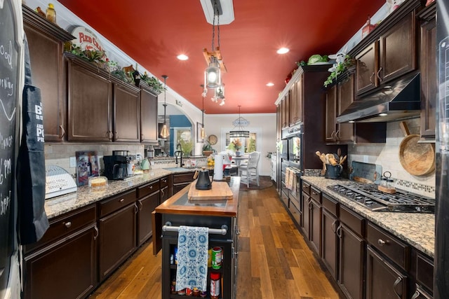 5000 Moretto Ct, Spring Hill, TN 37174 - kitchen with under cabinet range hood, decorative backsplash, black appliances, and dark brown cabinets