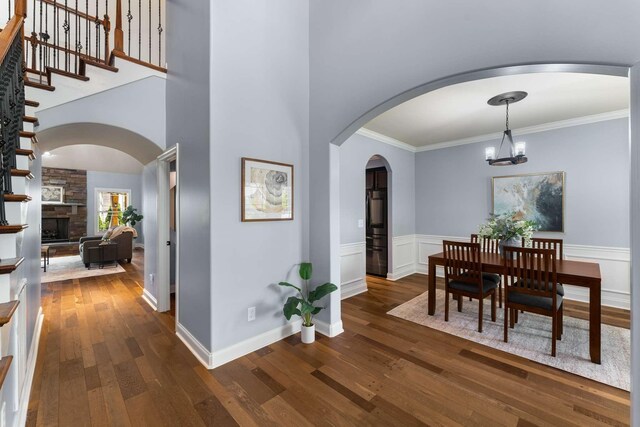 5000 Moretto Ct, Spring Hill, TN 37174 - dining space featuring dark wood-style floors, a chandelier, a stone fireplace, ornamental molding, and arched walkways