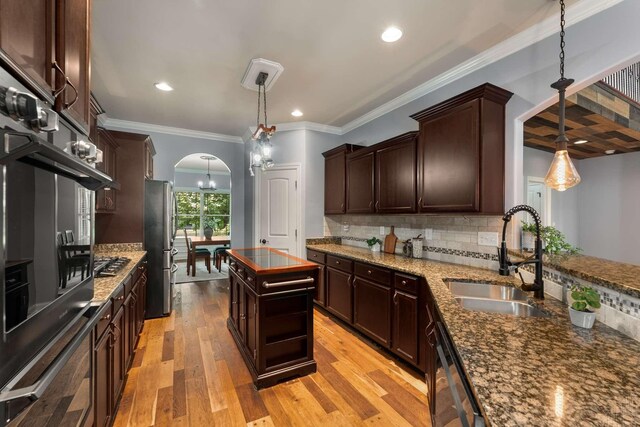 5000 Moretto Ct, Spring Hill, TN 37174 - kitchen with arched walkways, stainless steel appliances, dark brown cabinetry, decorative backsplash, and light wood finished floors