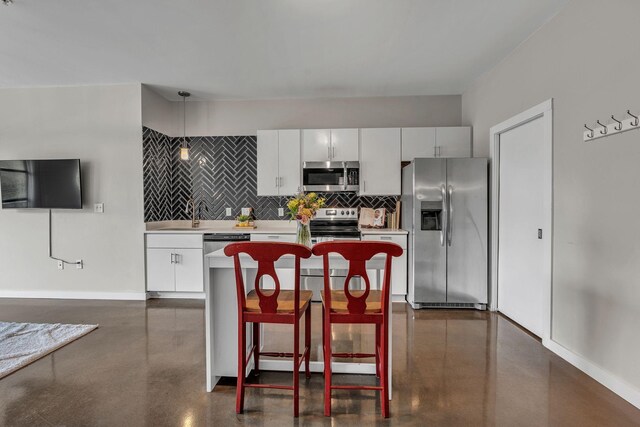 1900 12th Ave S Unit 219, Nashville, TN 37203 - kitchen featuring white cabinets, backsplash, light countertops, a kitchen island, and appliances with stainless steel finishes
