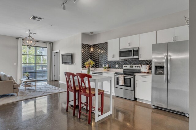 1900 12th Ave S Unit 219, Nashville, TN 37203 - kitchen featuring stainless steel appliances, light countertops, visible vents, pendant lighting, and decorative backsplash