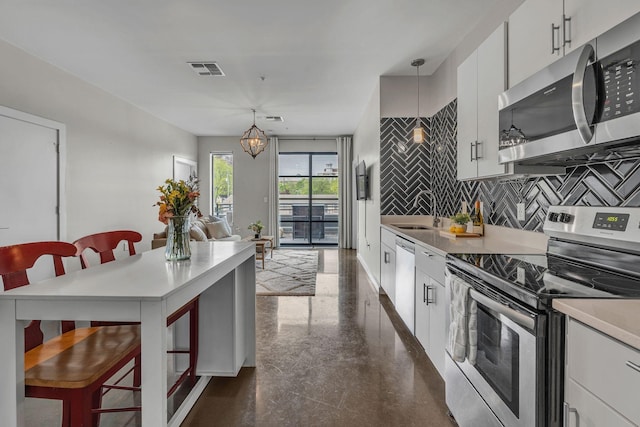 1900 12th Ave S Unit 219, Nashville, TN 37203 - kitchen featuring a sink, tasteful backsplash, visible vents, appliances with stainless steel finishes, and hanging light fixtures