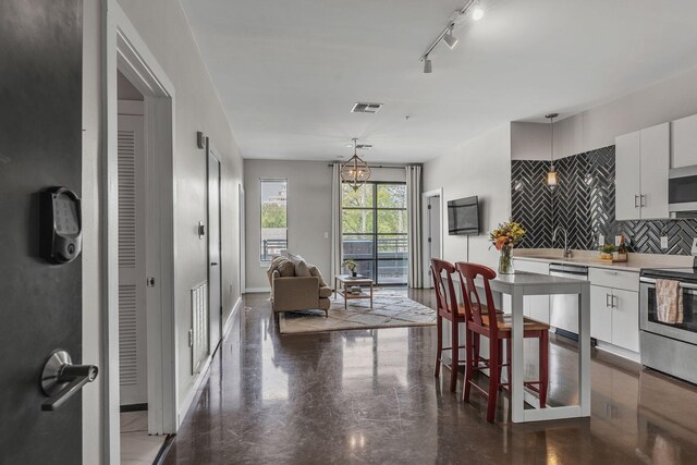 1900 12th Ave S Unit 219, Nashville, TN 37203 - kitchen with decorative light fixtures, tasteful backsplash, white cabinetry, and stainless steel appliances