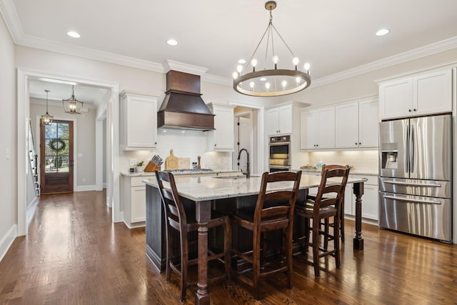 kitchen featuring a kitchen island with sink, a sink, a chandelier, custom range hood, and appliances with stainless steel finishes