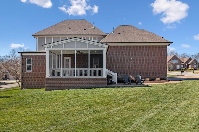 rear view of house featuring brick siding, a sunroom, ceiling fan, and a lawn