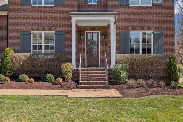property entrance with brick siding and a lawn