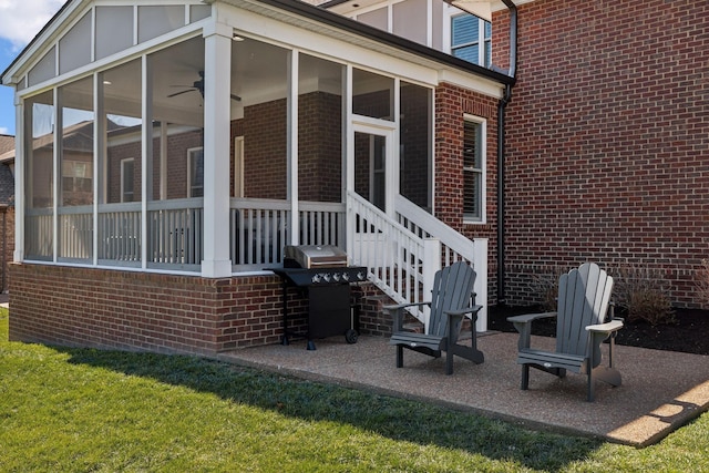 back of house featuring a yard, a sunroom, brick siding, and a patio