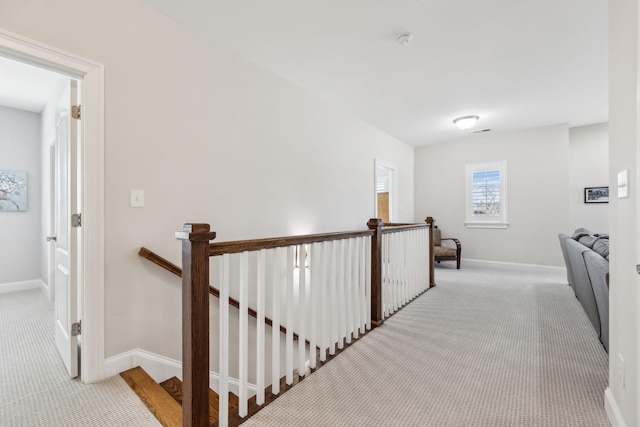 hall with baseboards, carpet floors, and an upstairs landing