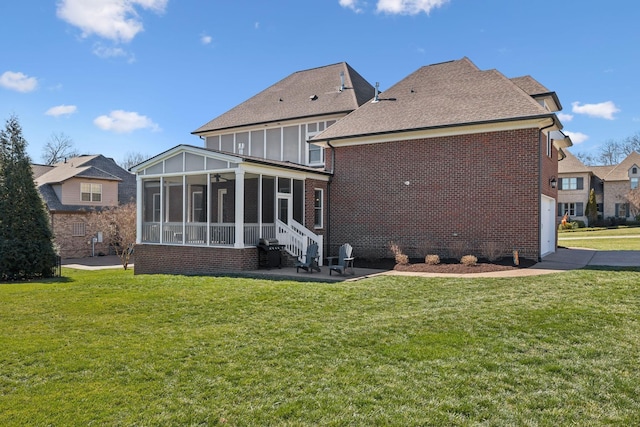 back of house featuring brick siding, a sunroom, and a lawn