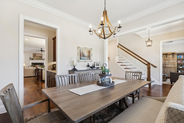 dining space with dark wood-style flooring, a chandelier, stairway, crown molding, and a lit fireplace