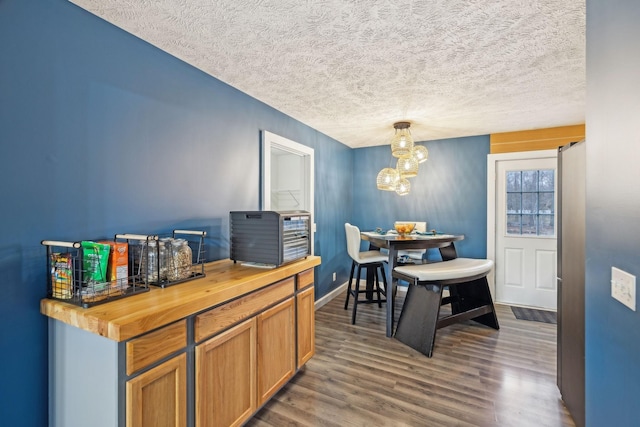 dining area featuring baseboards, an inviting chandelier, a textured ceiling, and dark wood finished floors