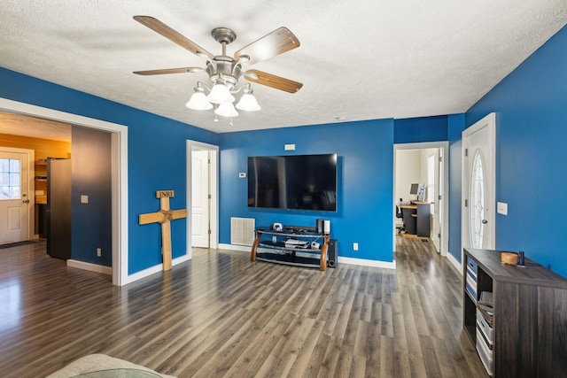 living room featuring a textured ceiling, wood finished floors, visible vents, and ceiling fan