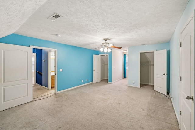 unfurnished bedroom featuring visible vents, light carpet, multiple closets, and baseboards