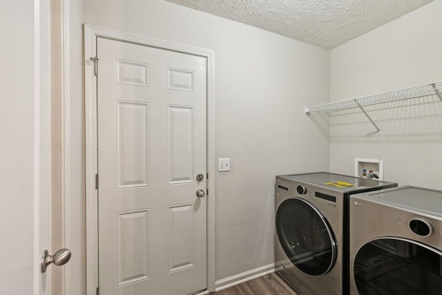 laundry area featuring a textured ceiling, washer and clothes dryer, dark wood-style flooring, baseboards, and laundry area