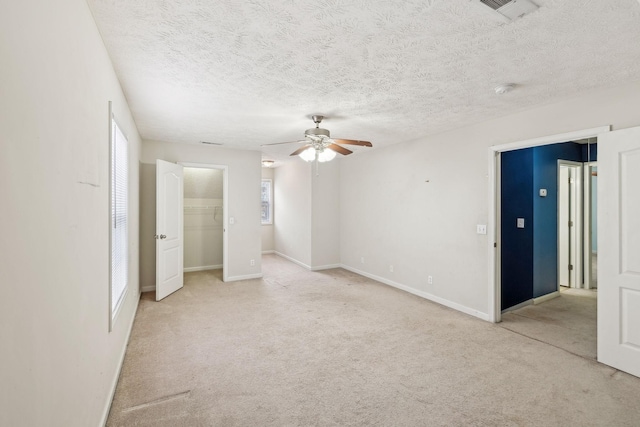 empty room featuring visible vents, light carpet, a ceiling fan, and baseboards