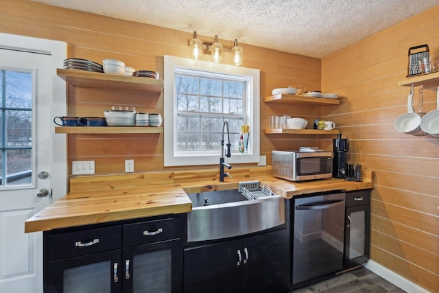 kitchen featuring stainless steel appliances, open shelves, butcher block countertops, and dark cabinetry