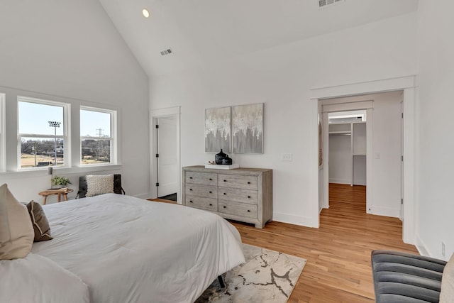 bedroom featuring high vaulted ceiling, baseboards, light wood-style floors, and visible vents