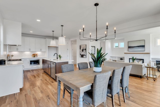 dining space with light wood finished floors, an inviting chandelier, and recessed lighting