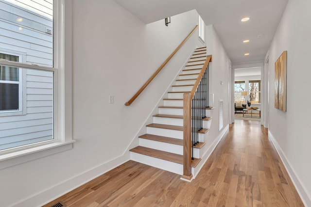 staircase with baseboards, wood finished floors, and recessed lighting