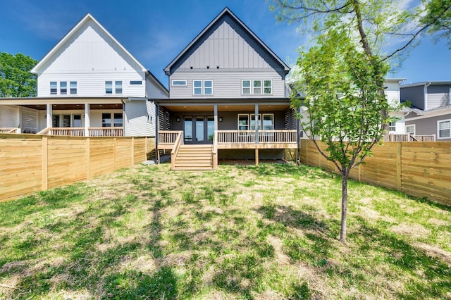 back of property with a fenced backyard, a yard, and board and batten siding