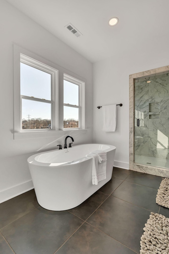 full bathroom with baseboards, a freestanding tub, a marble finish shower, and visible vents
