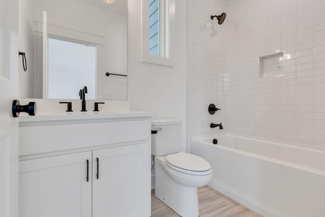 full bath with wood finished floors, vanity, washtub / shower combination, and toilet