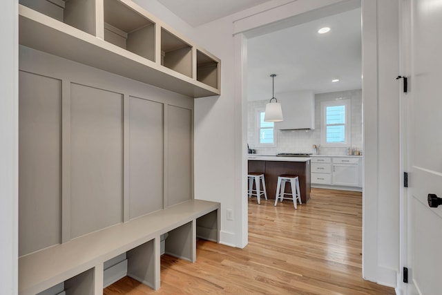 mudroom with recessed lighting, light wood-type flooring, and baseboards