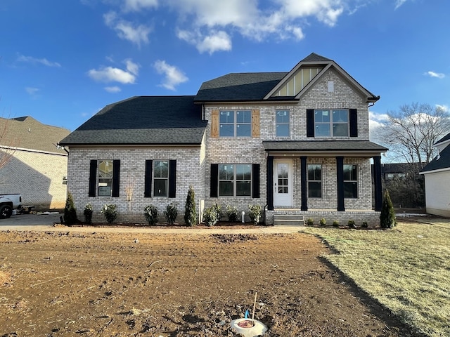 craftsman-style home featuring brick siding, roof with shingles, and covered porch