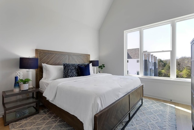 bedroom featuring lofted ceiling, baseboards, and wood finished floors