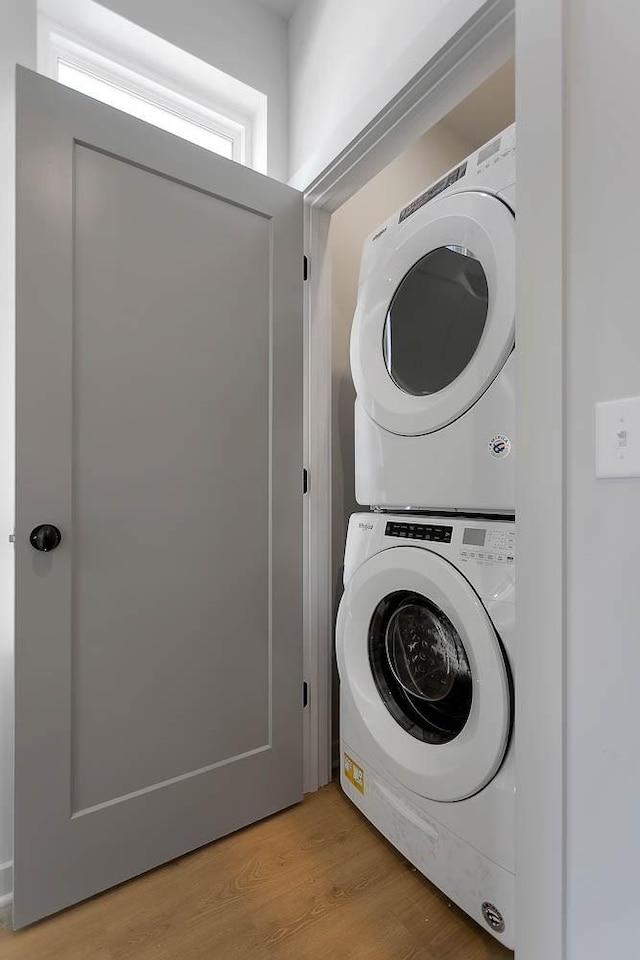 washroom featuring light wood-style floors, stacked washer / dryer, and laundry area