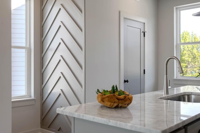 interior space with light stone countertops, white cabinets, and a sink