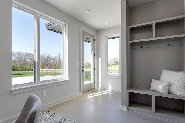 mudroom featuring baseboards, concrete flooring, and plenty of natural light