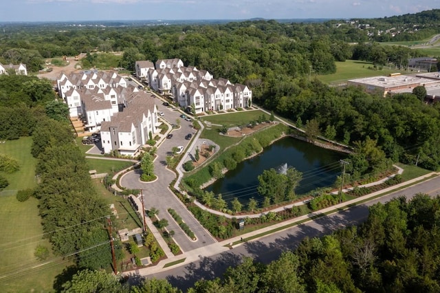 drone / aerial view featuring a view of trees, a water view, and a residential view