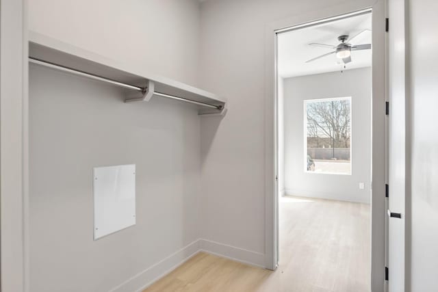 walk in closet with light wood-style flooring and ceiling fan