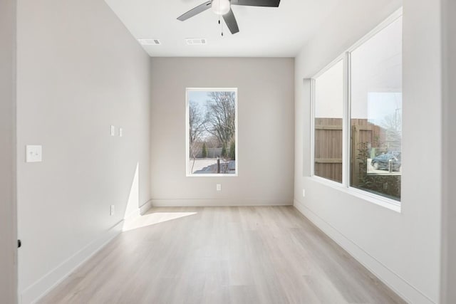 empty room with light wood-style floors, a ceiling fan, and baseboards