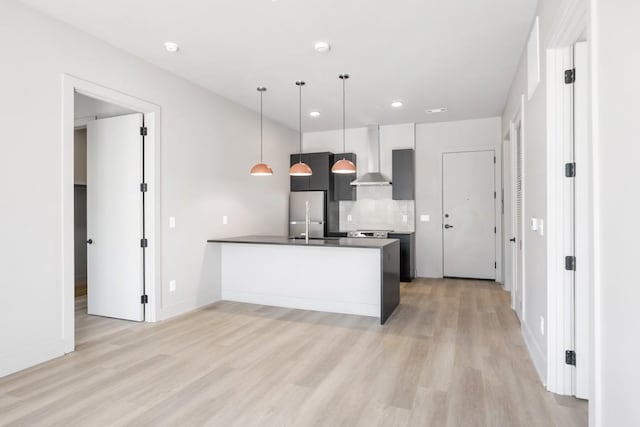 kitchen featuring wall chimney range hood, light wood-style floors, a peninsula, recessed lighting, and decorative backsplash