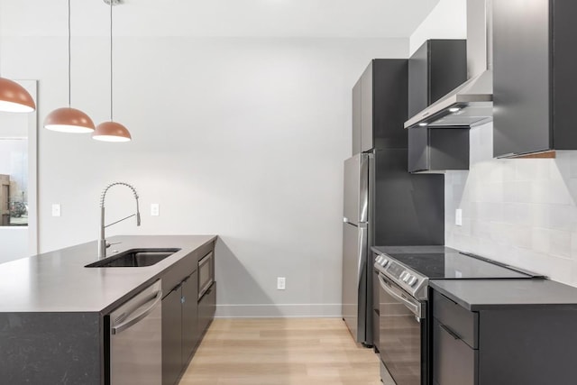 kitchen featuring appliances with stainless steel finishes, a sink, light wood-type flooring, decorative backsplash, and a peninsula