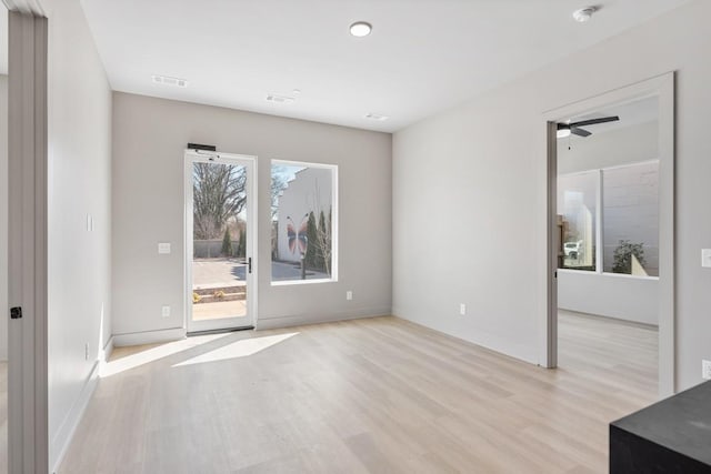 empty room featuring light wood-style floors, a smoke detector, a ceiling fan, and baseboards