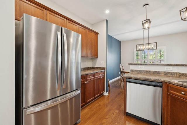 2142 Gold Valley Dr, Murfreesboro, TN 37130 - kitchen with decorative light fixtures, dark countertops, brown cabinets, wood finished floors, and stainless steel appliances