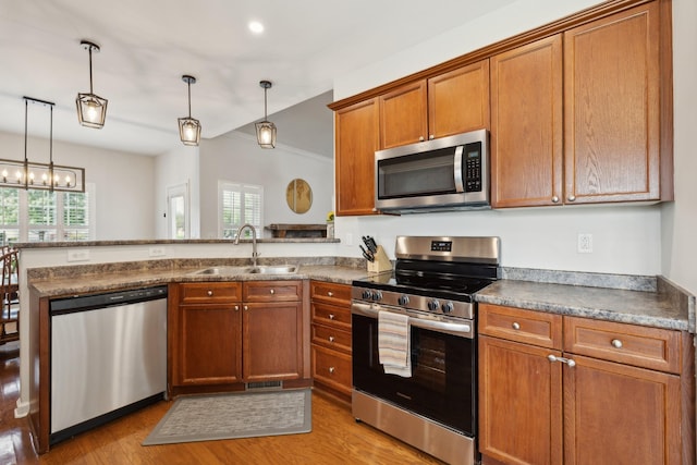 2142 Gold Valley Dr, Murfreesboro, TN 37130 - kitchen with brown cabinets, a sink, light wood finished floors, stainless steel appliances, and a peninsula