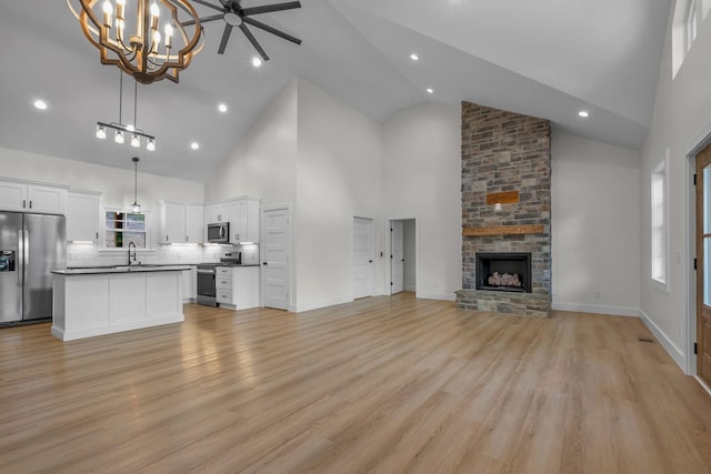 327 Turkey Creek Highway, Carthage, TN 37030 - unfurnished living room with light wood-type flooring, high vaulted ceiling, a stone fireplace, and a sink