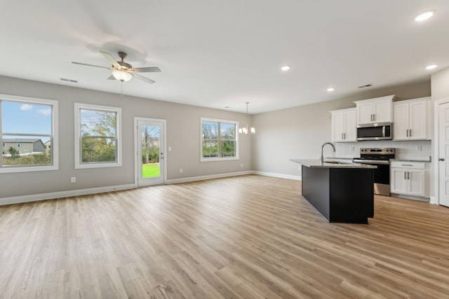 kitchen with decorative backsplash, open floor plan, stainless steel appliances, and light wood-style floors