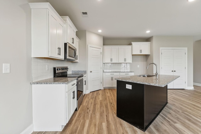 kitchen with a sink, decorative backsplash, stainless steel appliances, light wood finished floors, and baseboards