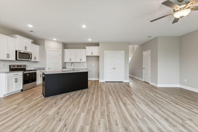 kitchen featuring white cabinets, stainless steel appliances, baseboards, and light wood finished floors