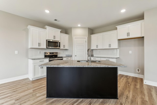 kitchen featuring stainless steel appliances, a sink, visible vents, backsplash, and white cabinetry