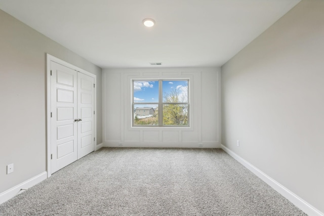 spare room with carpet floors, visible vents, and baseboards