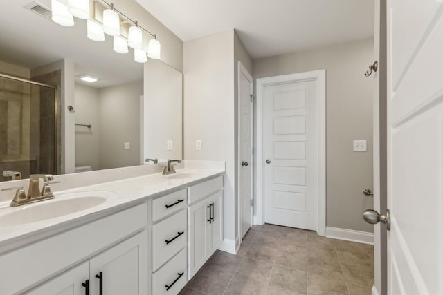 bathroom featuring double vanity, toilet, a stall shower, and a sink