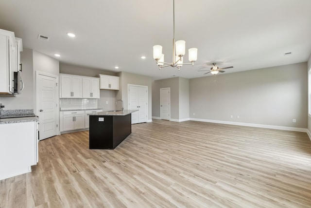 kitchen with light wood finished floors, open floor plan, visible vents, ceiling fan with notable chandelier, and hanging light fixtures