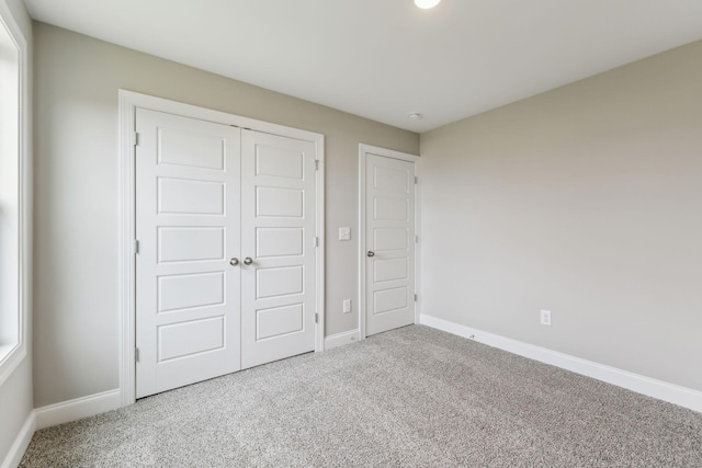 unfurnished bedroom with carpet floors, a closet, and baseboards